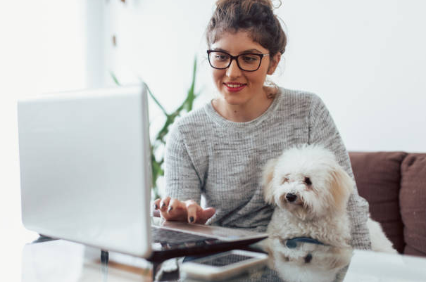 Colaboradora com seu notebook e pet ao colo após consulta pela telemedicina veterinária.